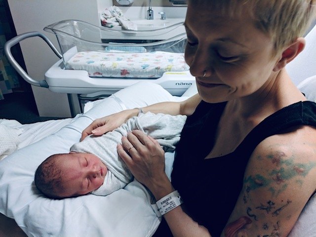 Author smiling next to her sleeping newborn