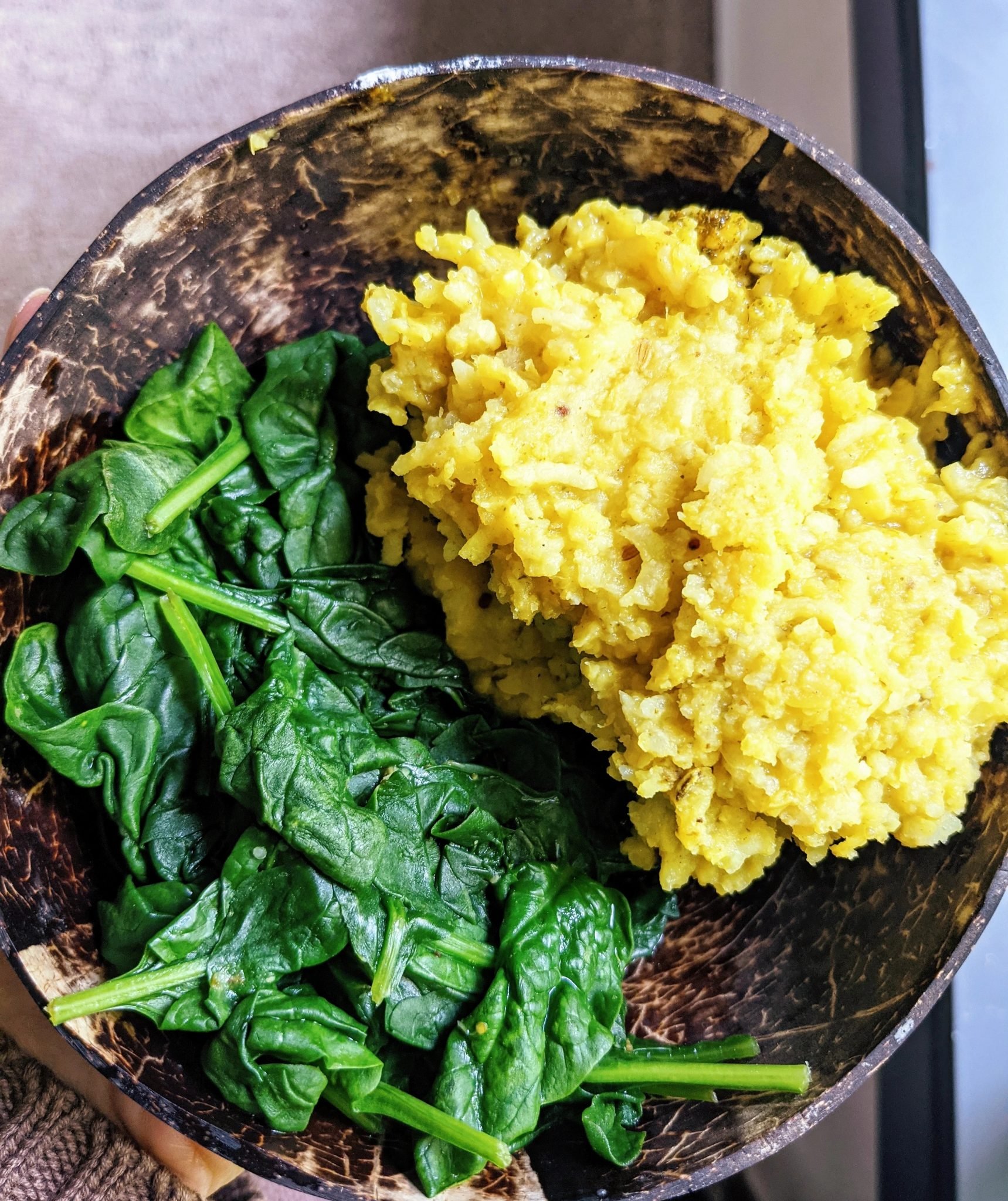 kitchari in a coconut bowl with spinach