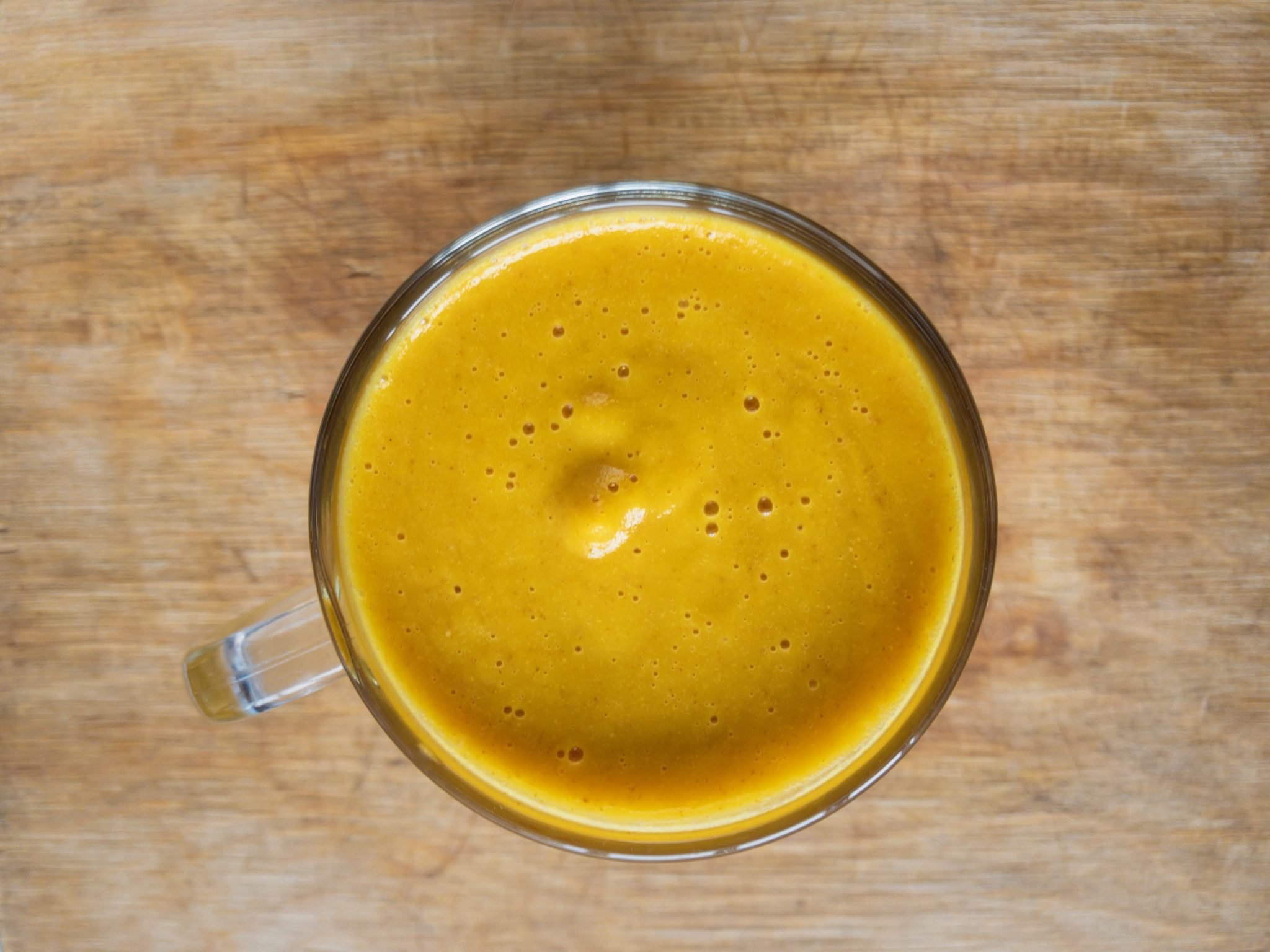 yellow/orange smoothie in a glass, bird's eye view