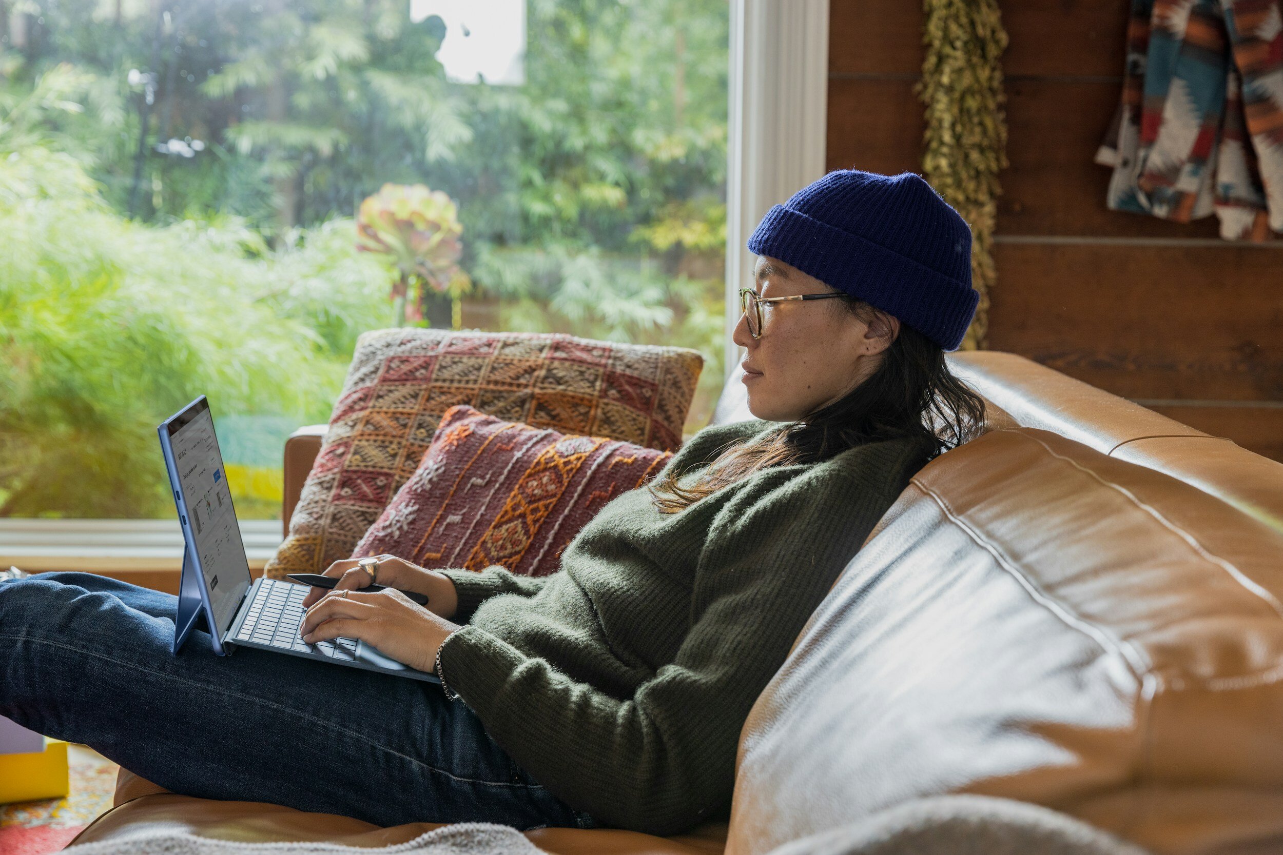 Asian woman sitting on a couch with her laptop.