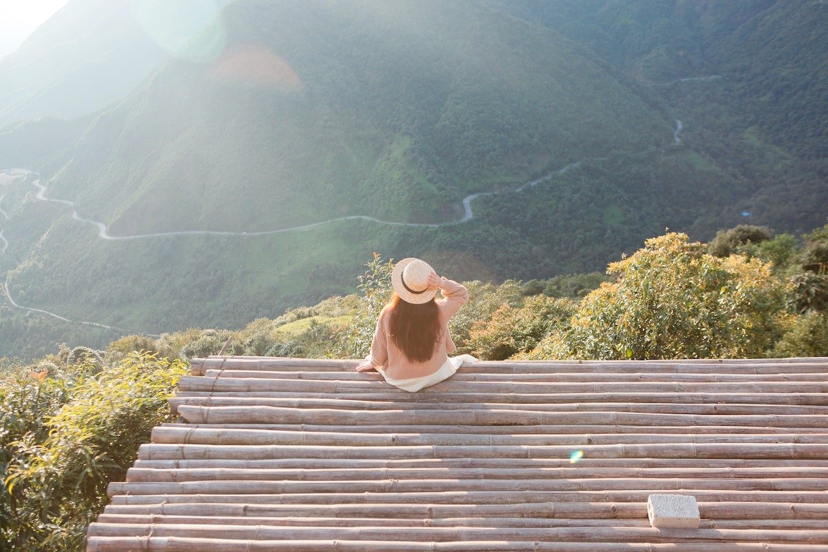 woman from the back, sitting, looking at a gorgeous mountain view.