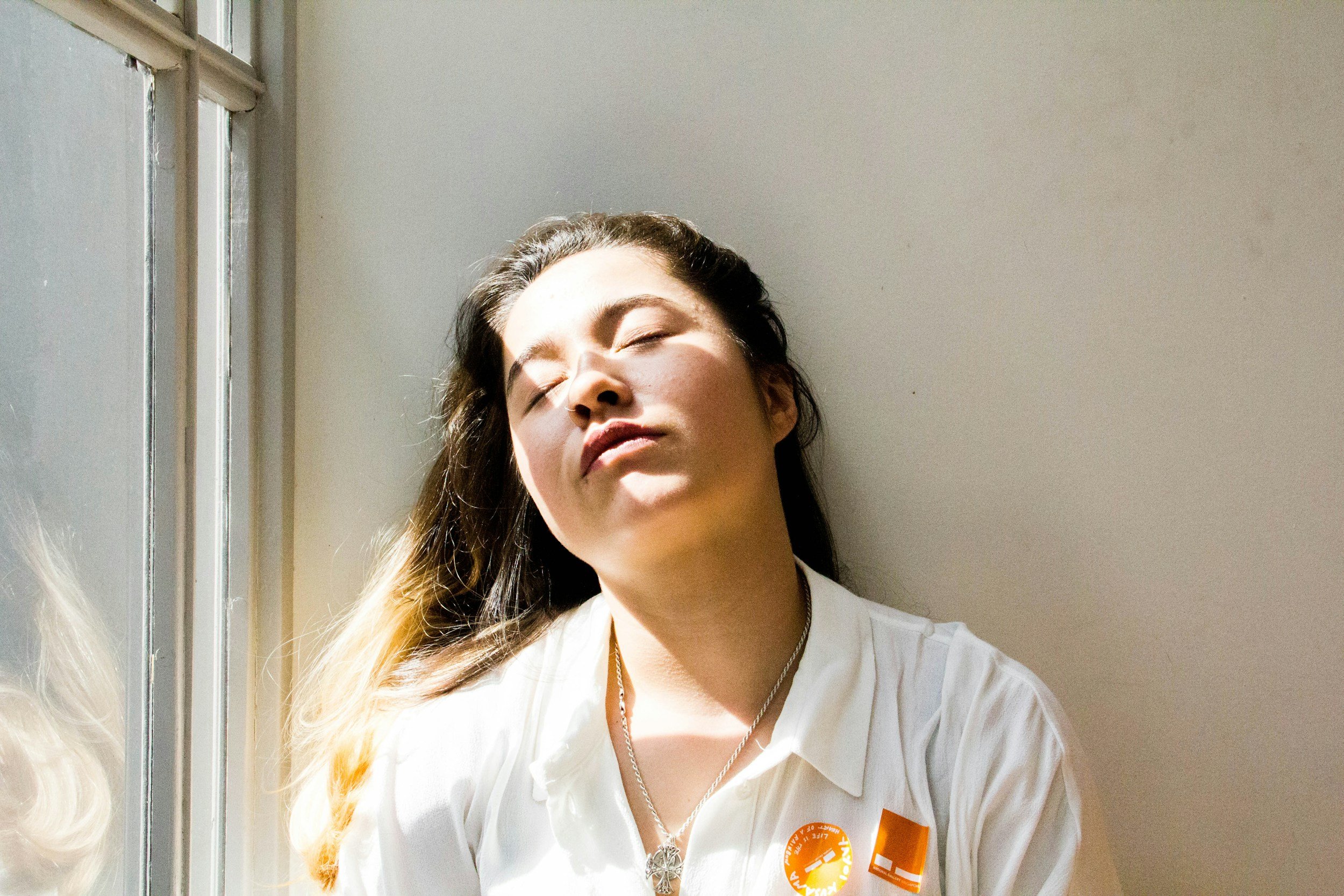 Sunlight on a tired-looking young woman with long hair