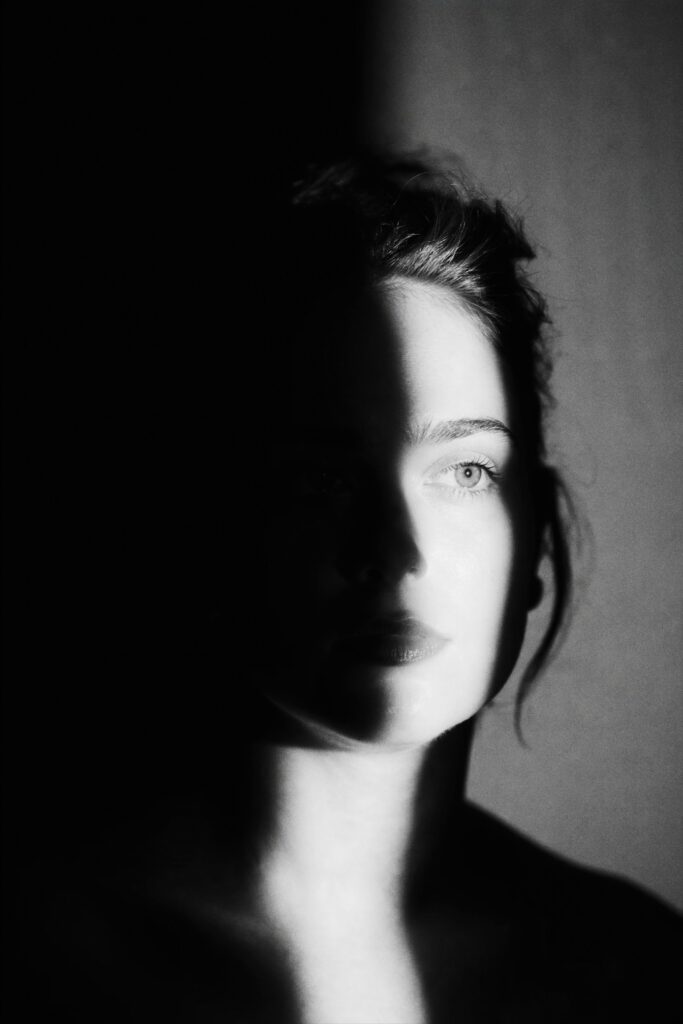 Woman_s profile partially obscured by dramatic shadow and uncertainty