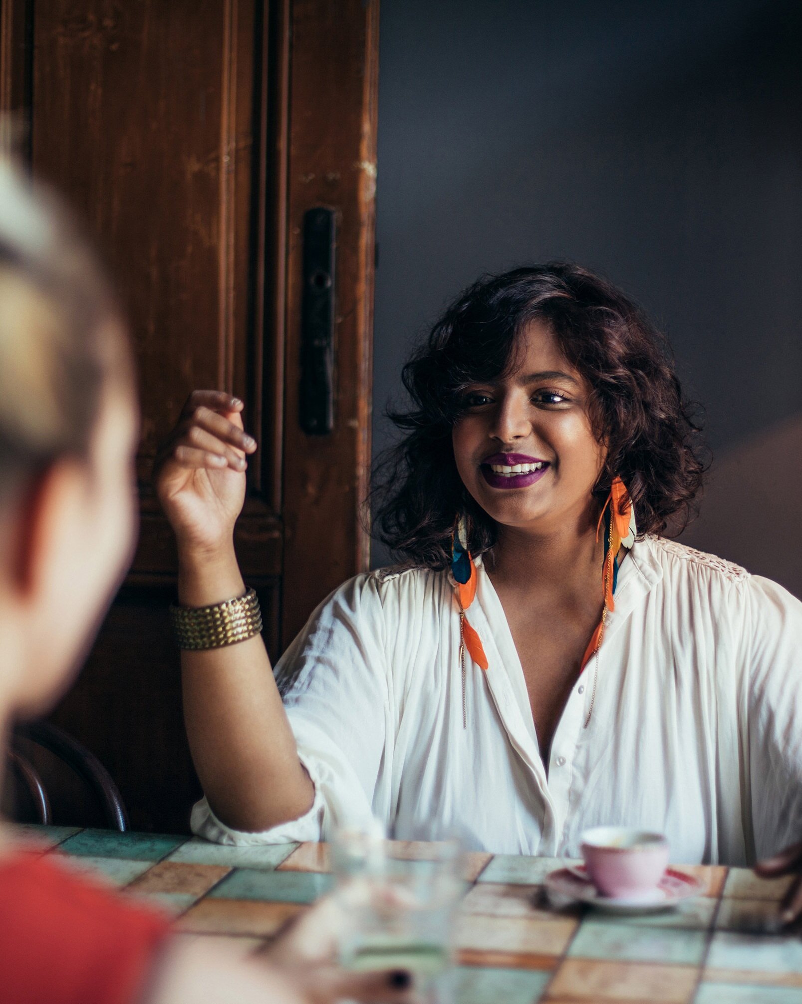 Woman with big rings and a statement bracelet smiling at the person in front of her.