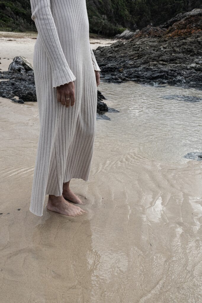 Dusk - Woman in white dress wading in shallow coastal waters - TVS