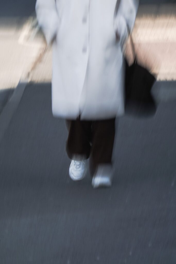Person walking in white trainers outdoors.