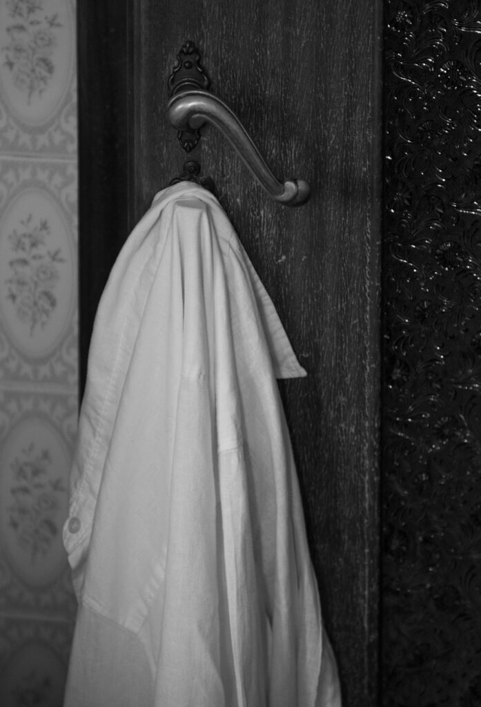 Black and white picture of a woman's button down shirt on a door hook.