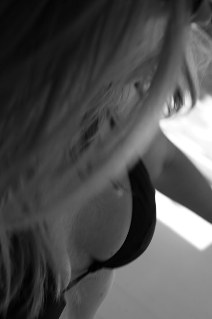 As a part of her Ayurvedic morning routine, a woman is engaged in a yoga practice in a well-lit indoor area. Sunlight filters through the window, highlighting her focused expression and graceful movements.