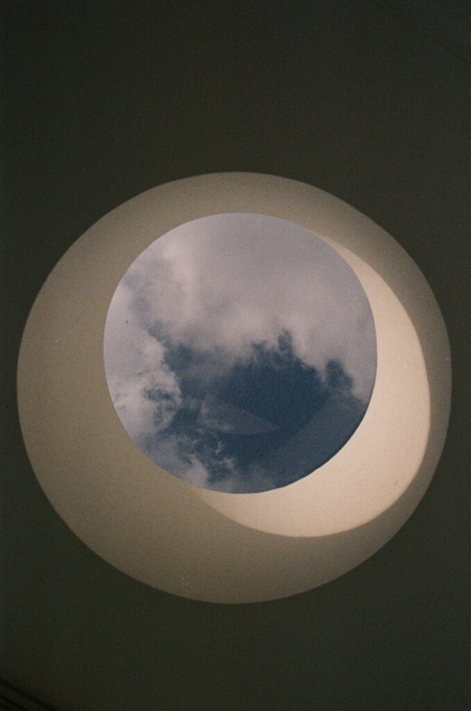 Clouds in a blue sky seen through a round window.