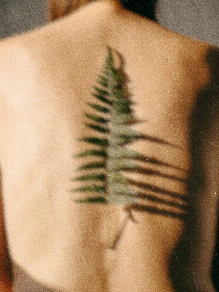 Nature-inspired fern leaf tattoo on bare back