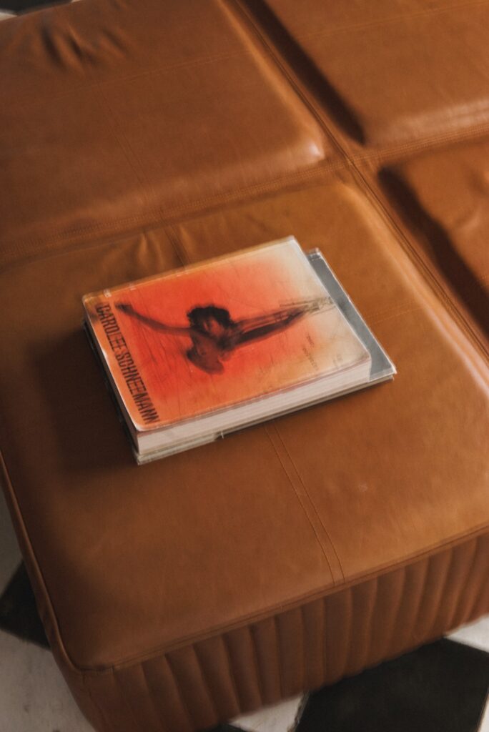 CD album with orange cover resting on brown leather sofa
