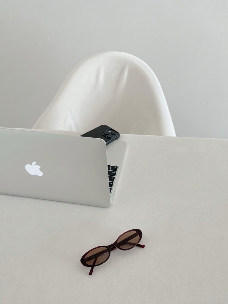 Minimalist workspace setup with laptop_ sunglasses_ and white sculpture