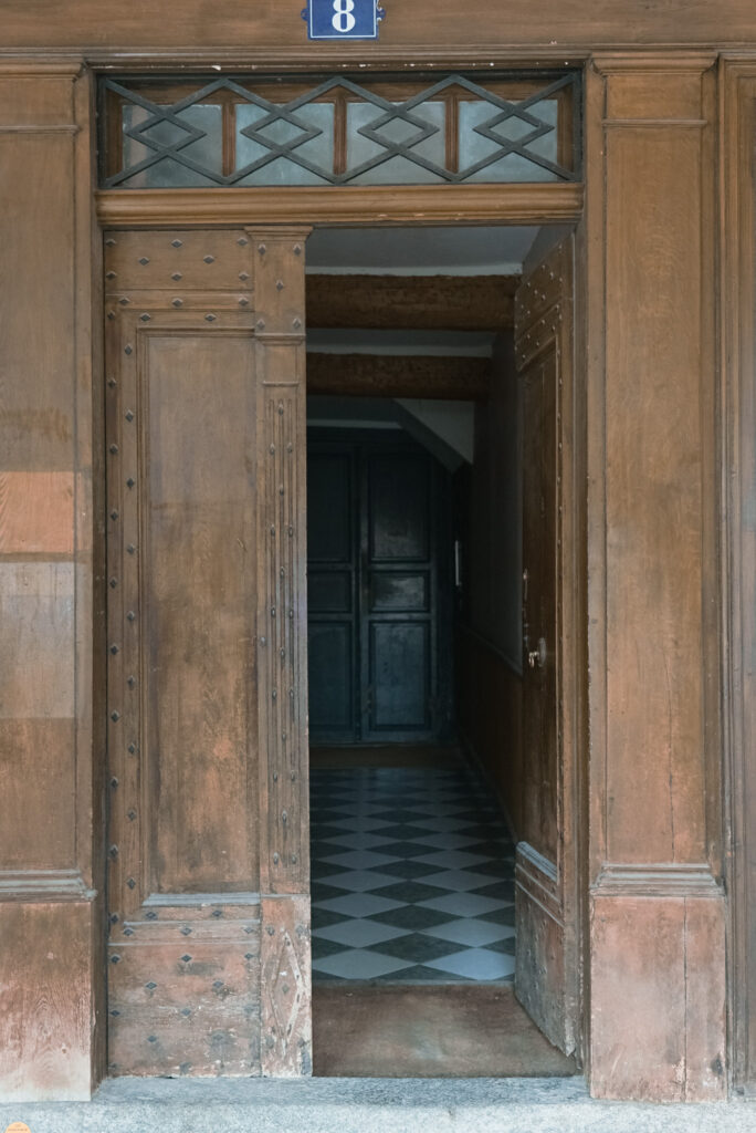 Historic wooden doorway with decorative transom and number eight