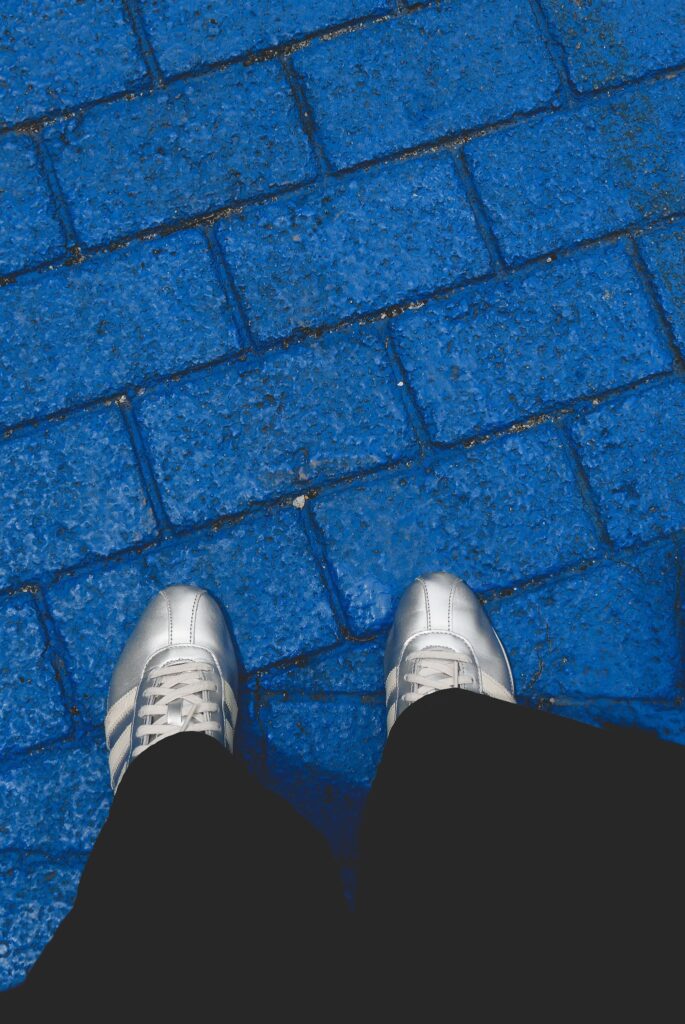 Silver sneakers standing on vibrant blue brick pavement