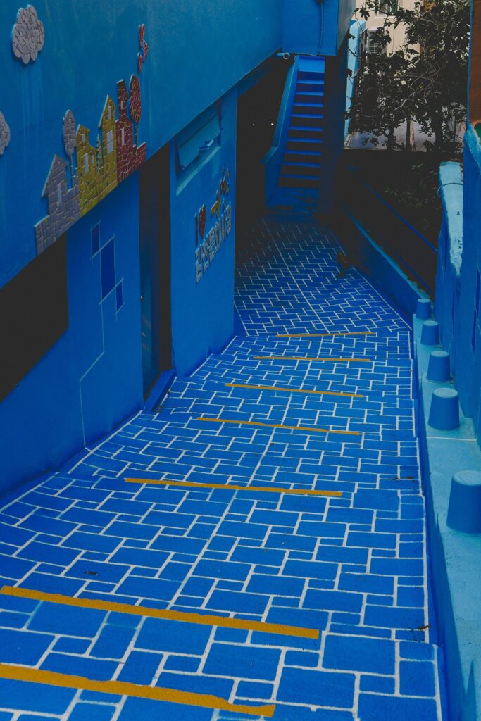 Vibrant blue alleyway with yellow-striped tile flooring 