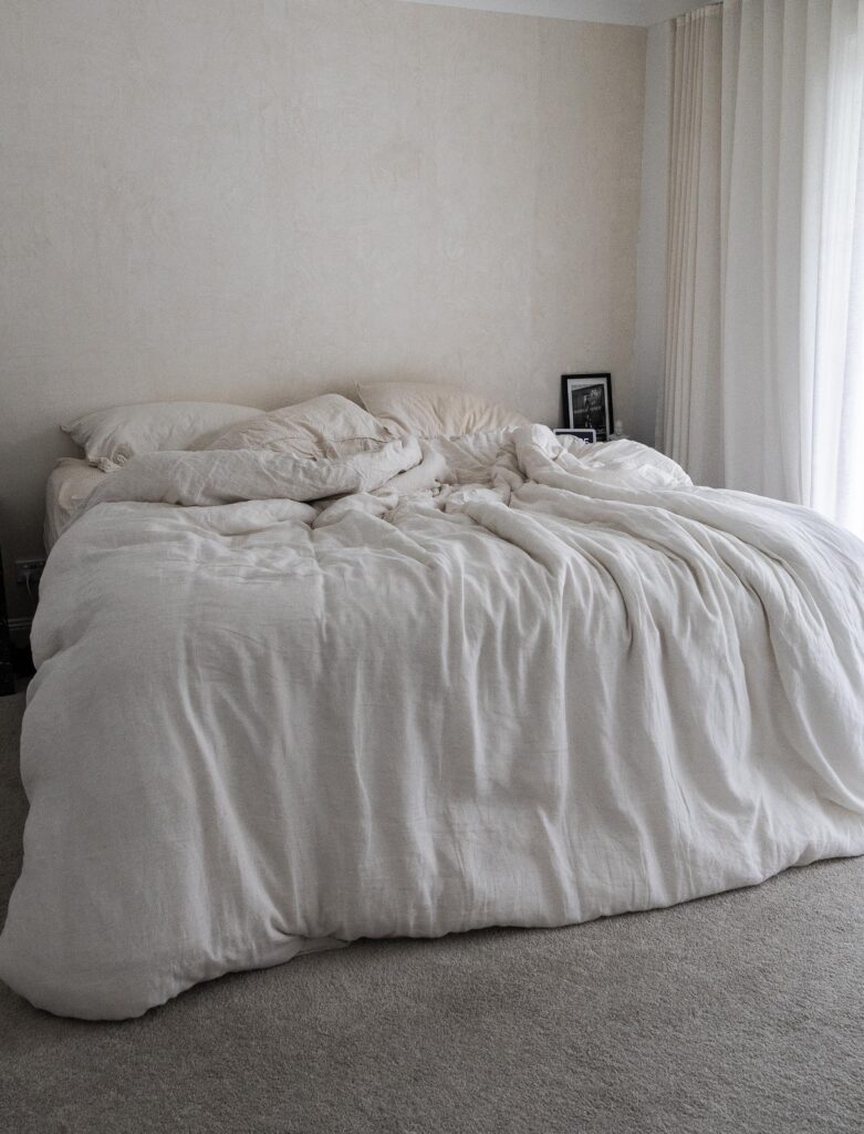 Minimalist bedroom with unmade bed and white linens