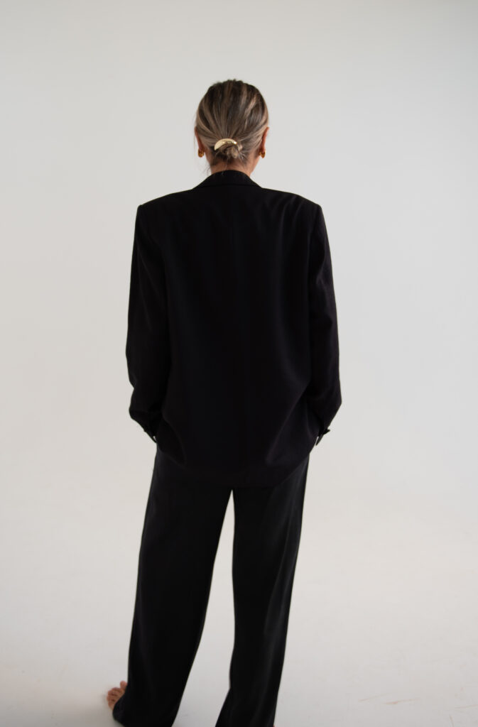 Professional woman in black suit standing confidently_ rear view