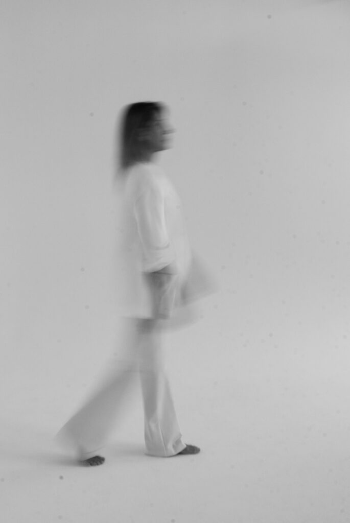 Woman in white clothing standing against minimal background